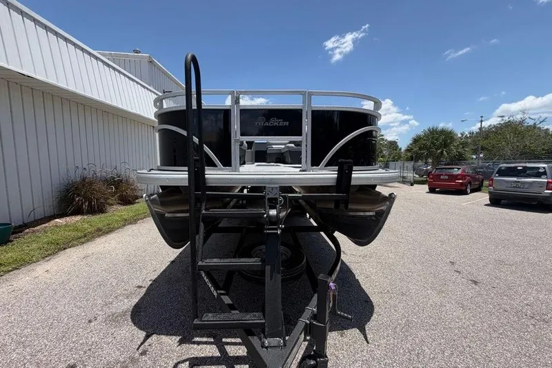 Slide: The Image of 2026 Sun Tracker Sportfish 24 XP3 pontoon boat on trailer, parked outdoors. - 98