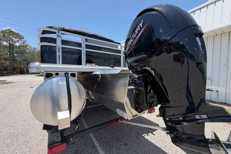 Slide: The Image of 2026 Sun Tracker Sportfish 24 XP3 pontoon boat with Mercury outboard motor, parked outdoors. - 3
