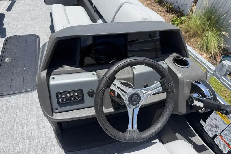 Slide: The Image of 2026 Sun Tracker Sportfish 24 XP3 boat dashboard with steering wheel and controls. - 2