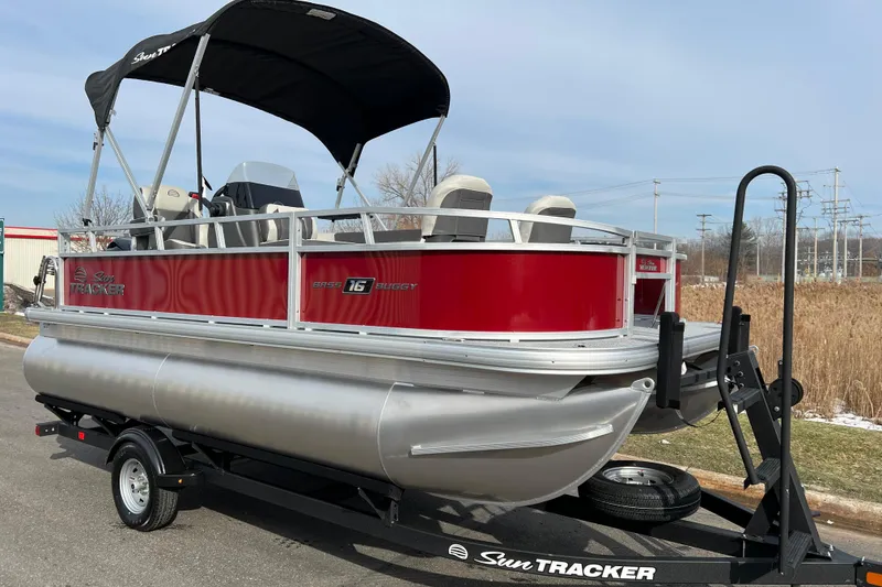 Slide: The Image of 2026 Sun Tracker Bass Buggy 16 XL Select pontoon boat on trailer, red and silver design. - 2