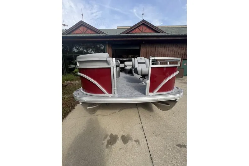 Slide: The Image of 2026 Sun Tracker SportFish 20 DLX pontoon boat with red exterior, parked outdoors. - 4