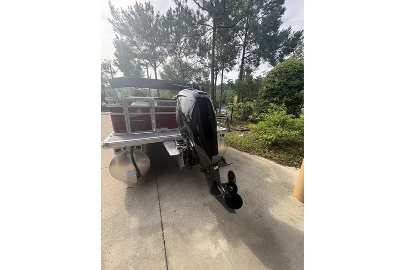 Slide: The Image of 2026 Sun Tracker SportFish 20 DLX pontoon boat with outboard motor, parked outdoors. - 3