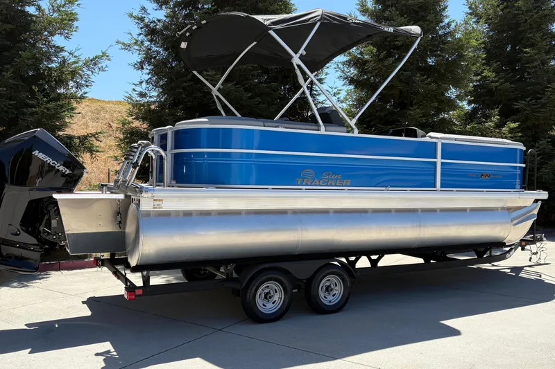 Slide: The Image of 2026 Sun Tracker Party Barge 22 XP3 pontoon boat on trailer, parked outdoors. - 2