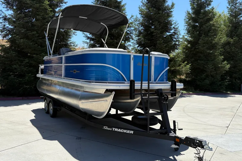 Slide: The Image of 2026 Sun Tracker Party Barge 22 XP3 pontoon boat on trailer, parked outdoors. - 10