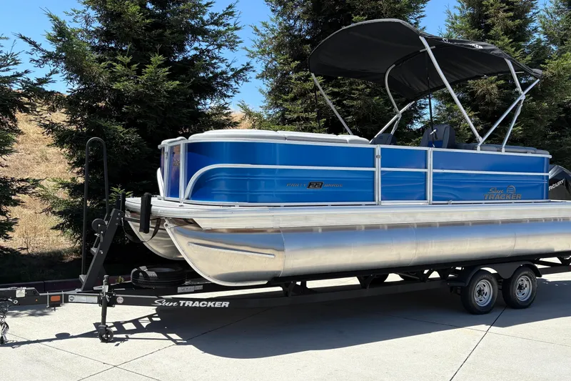 Slide: The Image of 2026 Sun Tracker Party Barge 22 XP3 pontoon boat on trailer, parked outdoors. - 6