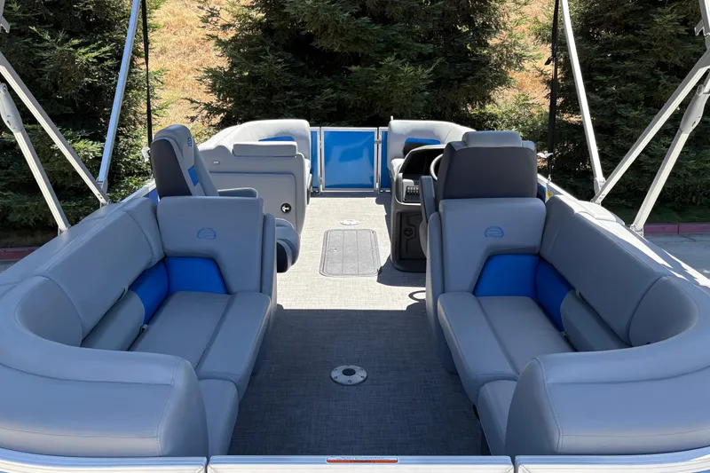 Slide: The Image of 2026 Sun Tracker Party Barge 22 XP3 interior with gray and blue seating, surrounded by trees. - 14