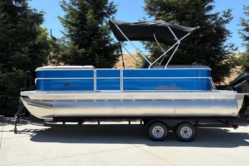 Slide: The Image of 2026 Sun Tracker Party Barge 22 XP3 pontoon boat on trailer, parked outdoors. - 8