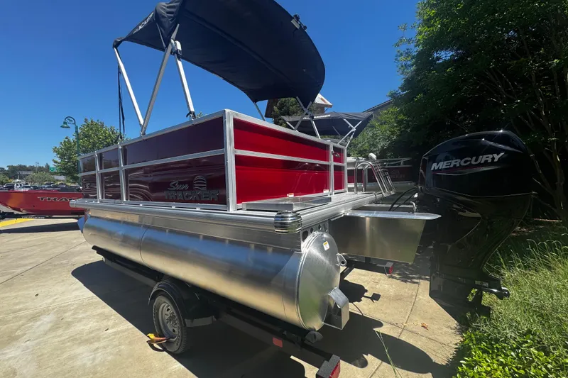 Slide: The Image of 2026 Sun Tracker Party Barge 16 DLX pontoon boat with Mercury engine, parked outdoors. - 2