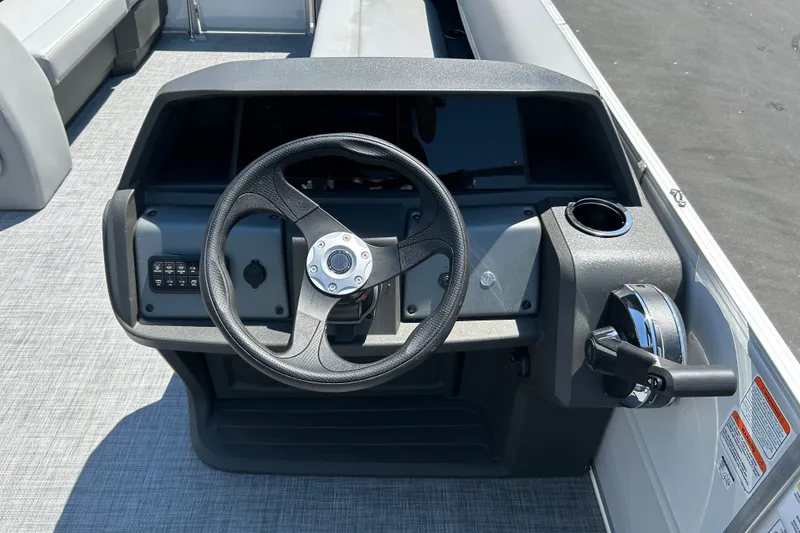 Slide: The Image of 2026 Sun Tracker Party Barge 18 DLX steering console with controls and cup holder. - 19
