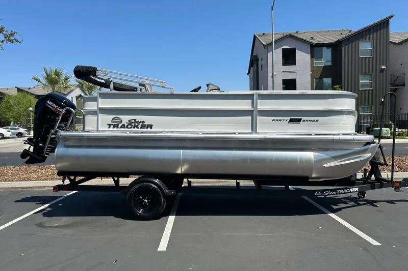 The Image of 2026 Sun Tracker Party Barge 18 DLX pontoon boat on trailer in parking lot. - 0