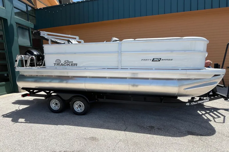 The Image of 2026 Sun Tracker Party Barge 20 DLX pontoon boat on trailer, parked outdoors. - 0
