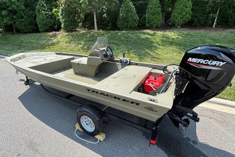Slide: The Image of 2026 Tracker Grizzly 1648 SC boat with Mercury engine on trailer, parked outdoors. - 6