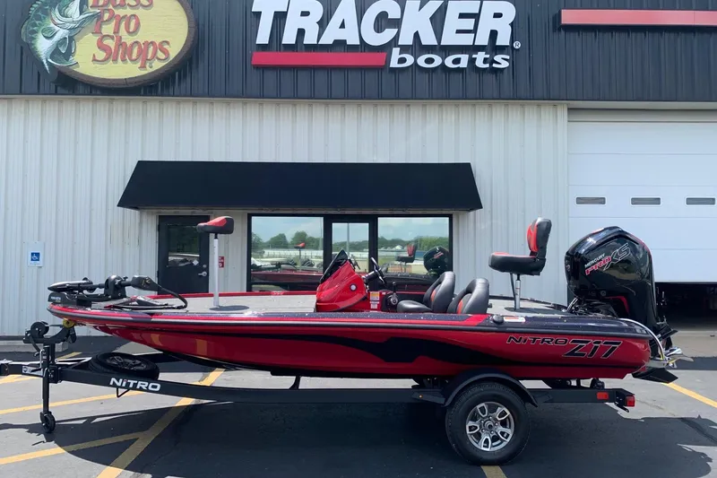 The Image of 2026 Nitro Z17 boat in red, parked outside Bass Pro Shops Tracker Boats store. - 0