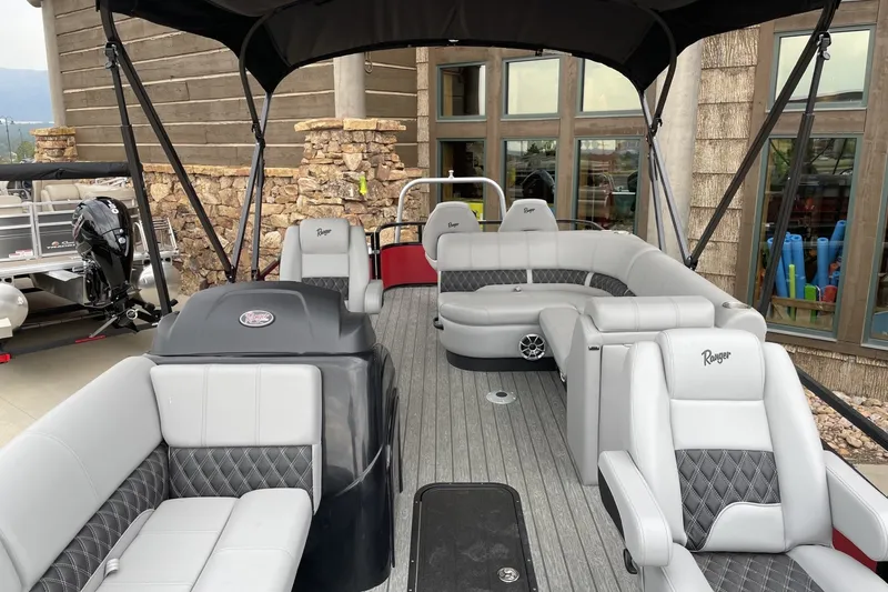 Slide: The Image of 2026 Ranger 223FC boat with luxurious seating and modern design, docked near a rustic building. - 3