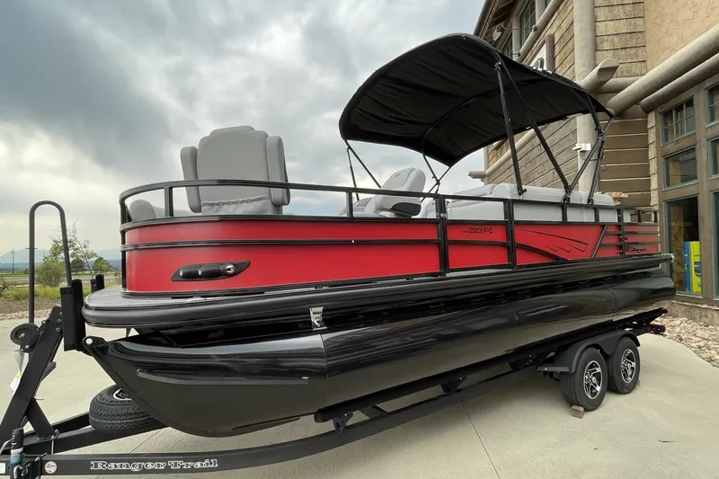 The Image of 2026 Ranger 223FC pontoon boat with red and black design on a trailer. - 0