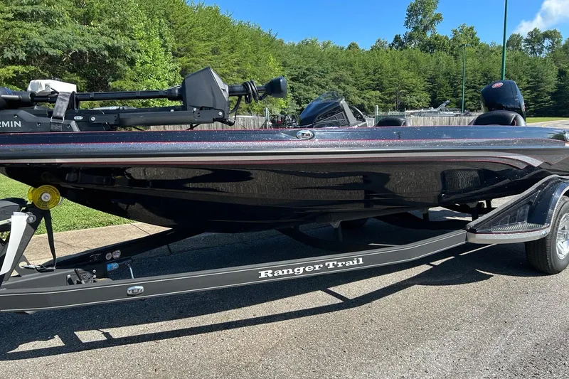 Slide: The Image of 2025 Ranger Z518 Cup-Equipped boat on trailer, parked outdoors with lush greenery. - 1