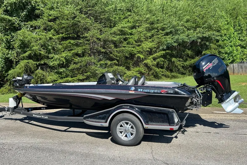 The Image of 2025 Ranger Z518 Cup-Equipped boat on trailer, parked on road with lush green background. - 0