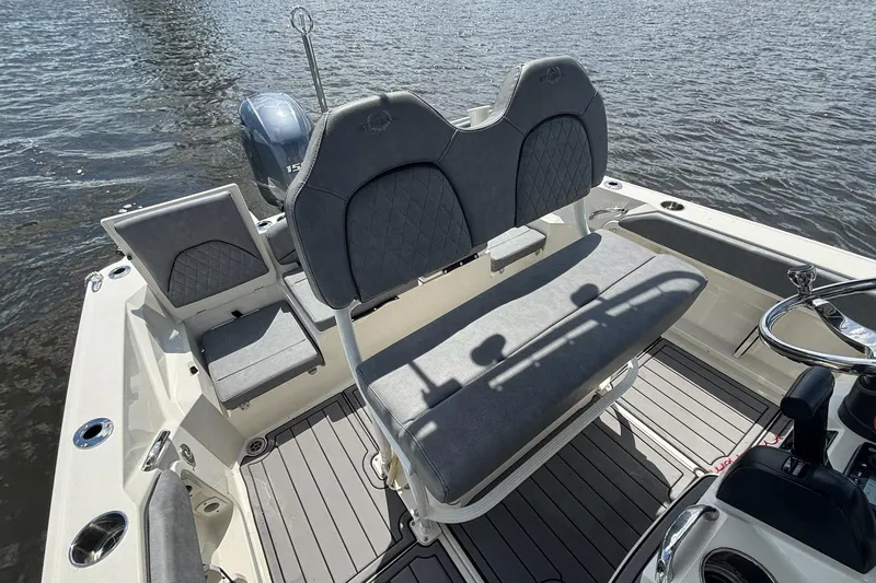 Slide: The Image of 2021 Stingray 216 CC boat interior with cushioned seating and steering wheel on the water. - 10