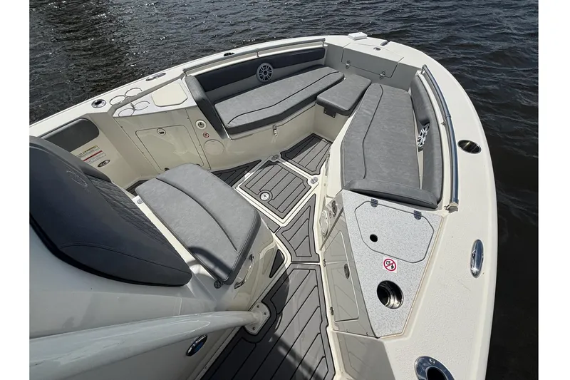 Slide: The Image of 2021 Stingray 216 CC boat interior with gray seating and deck, on water. - 18