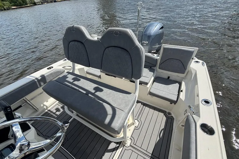 Slide: The Image of 2021 Stingray 216 CC boat interior with seating and steering wheel on water. - 19