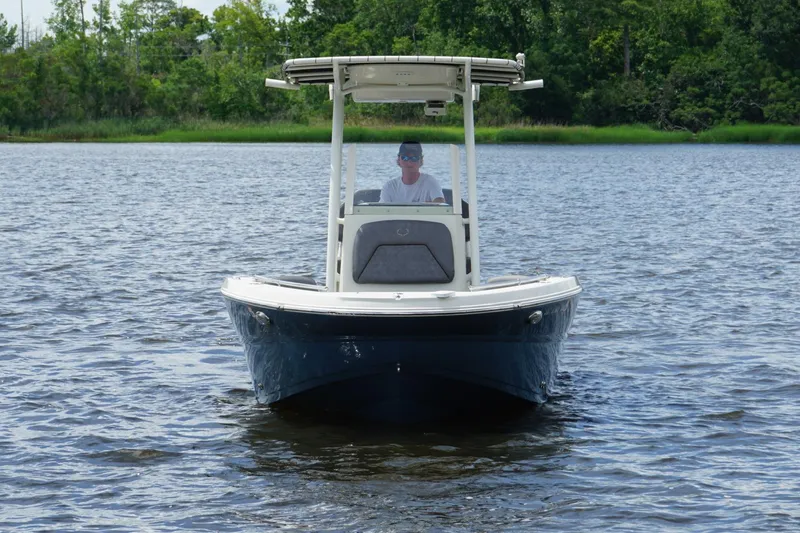 Slide: The Image of 2021 Stingray 216 CC boat on calm water, surrounded by lush greenery. - 2