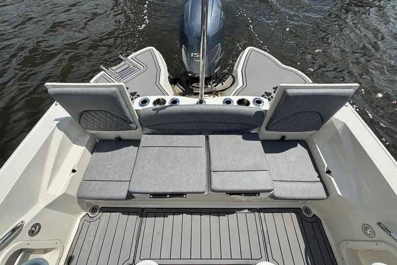 Slide: The Image of 2021 Stingray 216 CC boat interior with cushioned seating and outboard motor on water. - 22