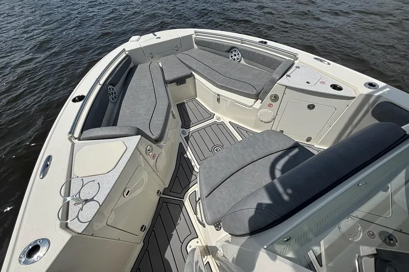 Slide: The Image of 2021 Stingray 216 CC boat interior with gray seating and cup holders on the water. - 7