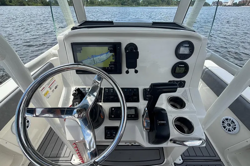 Slide: The Image of 2021 Stingray 216 CC boat dashboard with steering wheel, navigation screen, and controls on water. - 9