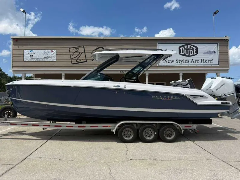 The Image of A Monterey Elite 30 OB boat on a trailer, parked in front of a building. - 0
