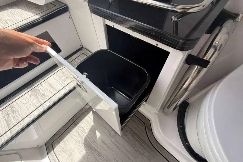 Slide: The Image of Hand opening storage compartment on 2026 Monterey Elite 30 OB boat. - 37