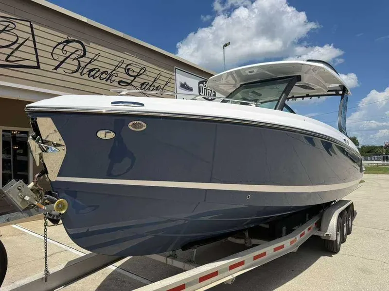 Slide: The Image of A 2026 Monterey Elite 30 OB boat on a trailer in front of a building. - 2