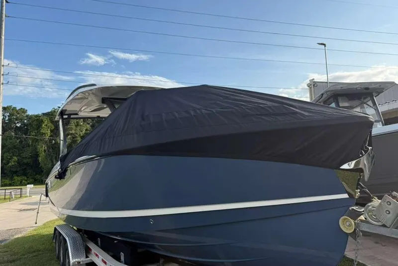 Slide: The Image of 2026 Monterey Elite 30 OB boat with cover on trailer, outdoors. - 94