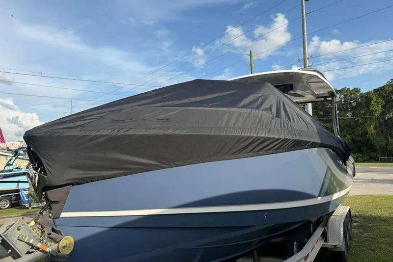 Slide: The Image of 2026 Monterey Elite 30 OB boat covered, parked on a trailer under a clear sky. - 89