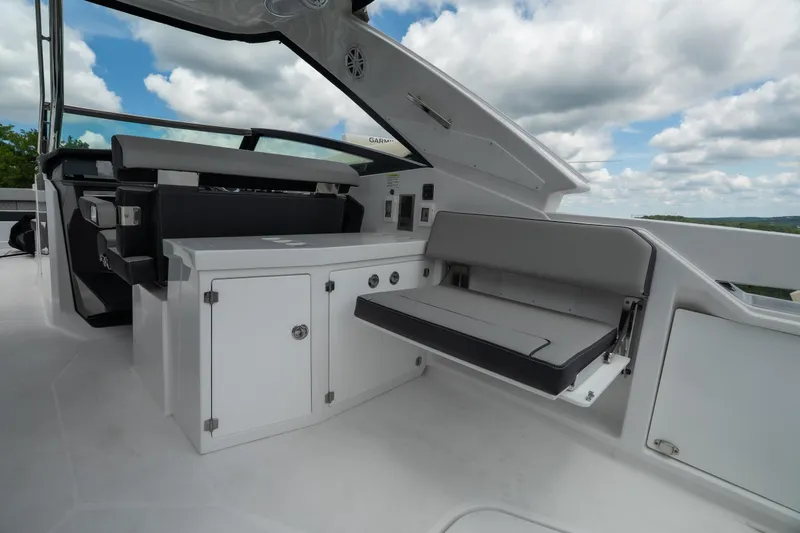 Slide: The Image of 2026 Monterey 385SS Super Sport boat interior with sleek seating and storage under a cloudy sky. - 11