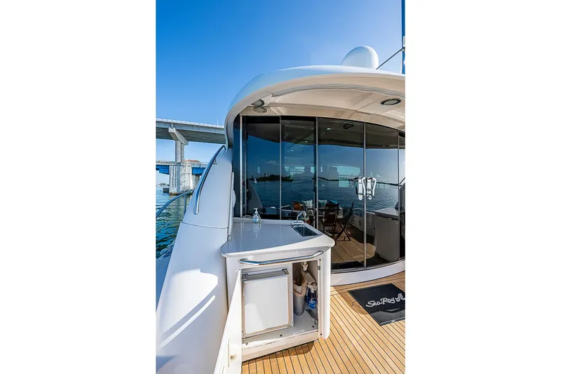 Slide: The Image of 2008 Sea Ray 60 Sundancer yacht with outdoor kitchenette and glass doors, docked near a bridge. - 65