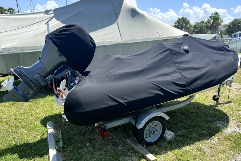 Slide: The Image of A covered boat on a trailer, parked on grass under a sunny sky. - 74