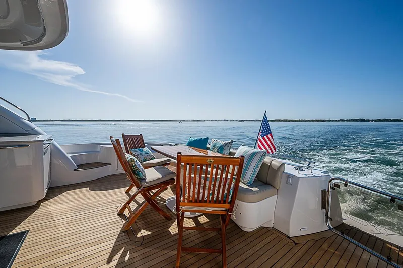 Slide: The Image of 2008 Sea Ray 60 Sundancer yacht deck with chairs, table, and American flag on open water. - 61