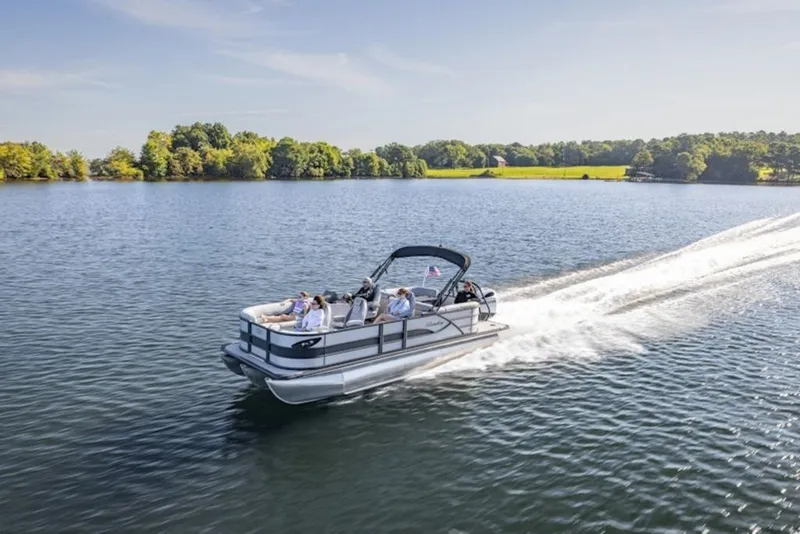 Slide: The Image of 2026 Bentley Pontoons Legacy 243 Swingback cruising on a serene lake under a clear sky. - 3