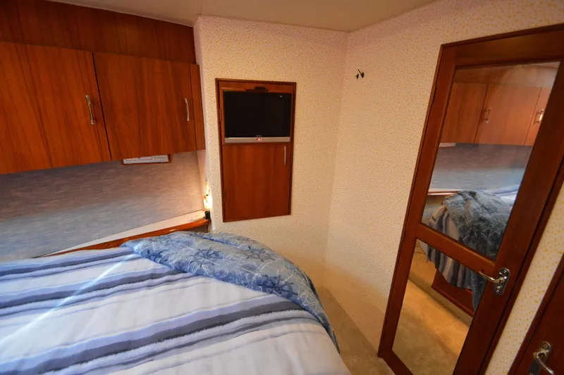 Slide: The Image of Cozy bedroom in 1995 Ocean 48 Cockpit Motor Yacht with wood cabinets and TV. - 43