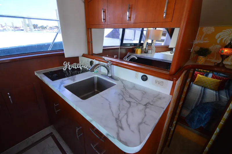 Slide: The Image of 1995 Ocean 48 Cockpit Motor Yacht kitchen with marble countertop and wooden cabinetry. - 27