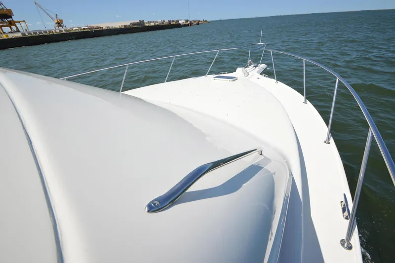 Slide: The Image of 1995 Ocean 48 Cockpit Motor Yacht cruising on open water near a harbor. - 72