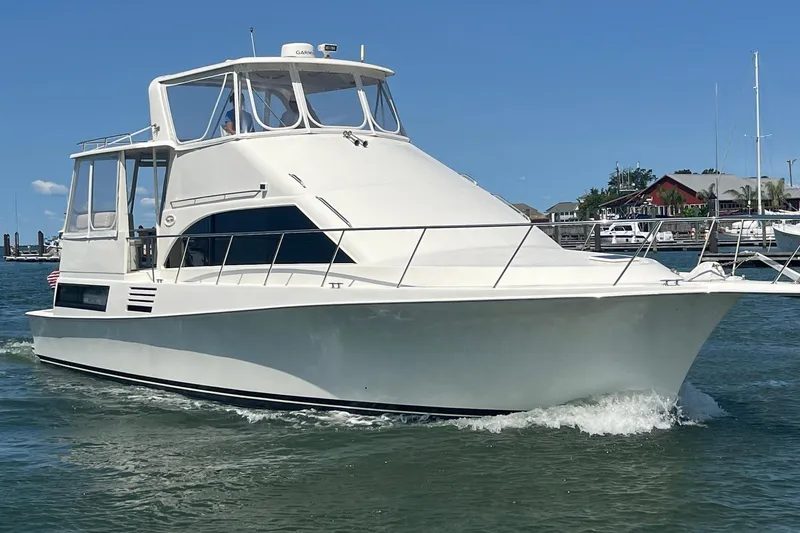 Slide: The Image of 1995 Ocean 48 Cockpit Motor Yacht cruising on a sunny day near a marina. - 89