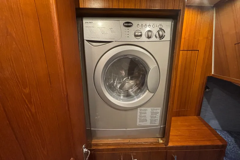 Slide: The Image of Built-in washing machine on 1995 Ocean 48 Cockpit Motor Yacht, surrounded by wooden cabinetry. - 34