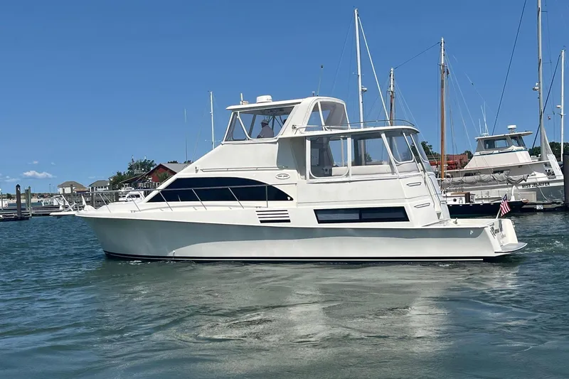 Slide: The Image of 1995 Ocean 48 Cockpit Motor Yacht cruising in a marina under clear blue skies. - 90