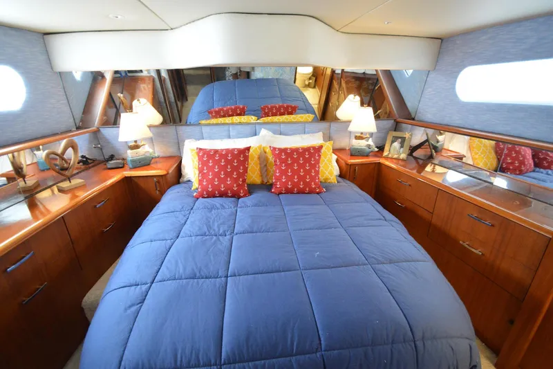 Slide: The Image of Luxurious bedroom interior of 1995 Ocean 48 Cockpit Motor Yacht with blue bedding and wooden cabinetry. - 31