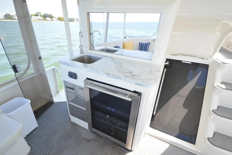 Slide: The Image of 1995 Ocean 48 Cockpit Motor Yacht interior with kitchenette, sink, and scenic water view. - 74
