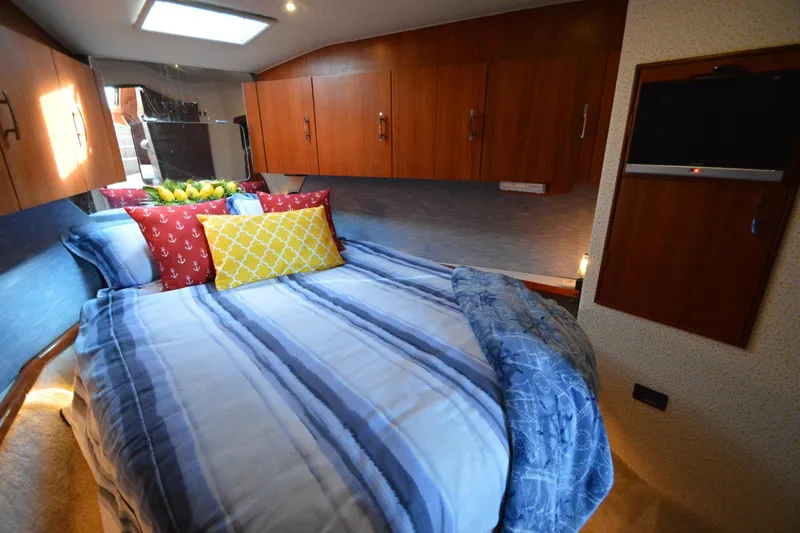 Slide: The Image of Cozy bedroom interior of 1995 Ocean 48 Cockpit Motor Yacht with striped bedding and wooden cabinets. - 40