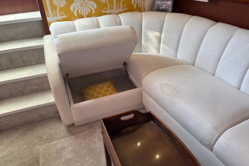 Slide: The Image of White sectional sofa with hidden storage, yellow pillow, and stairs in a 1995 Ocean 48 Cockpit Motor Yacht. - 18