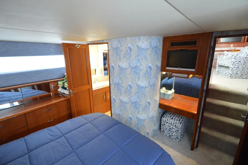 Slide: The Image of Luxurious 1995 Ocean 48 Cockpit Motor Yacht bedroom with blue bedding and wooden cabinetry. - 34