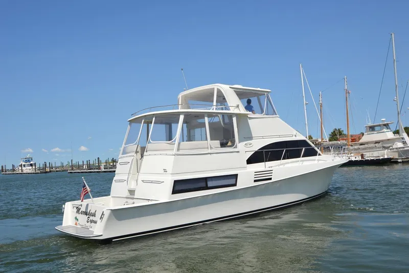 Slide: The Image of 1995 Ocean 48 Cockpit Motor Yacht cruising in a marina under clear blue skies. - 5